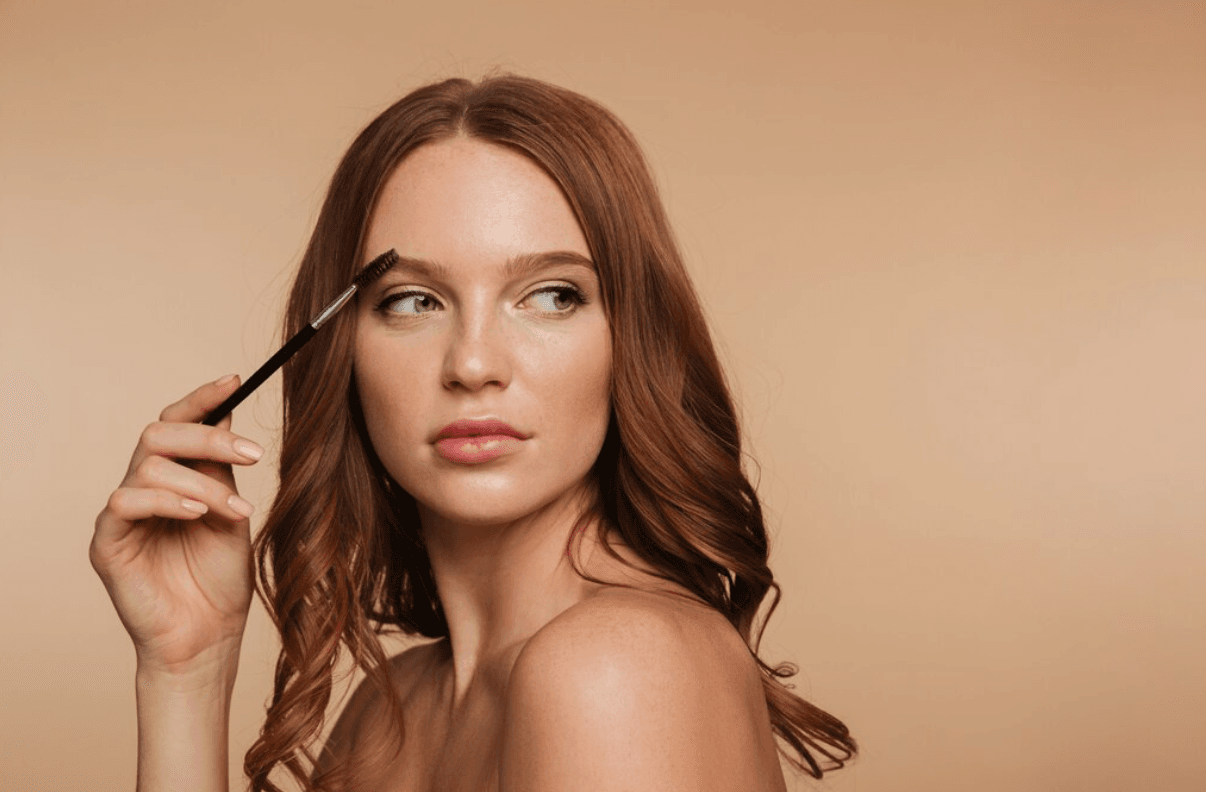 Жена, която държи  приспособление за разресване на вежди и сресва веждата си